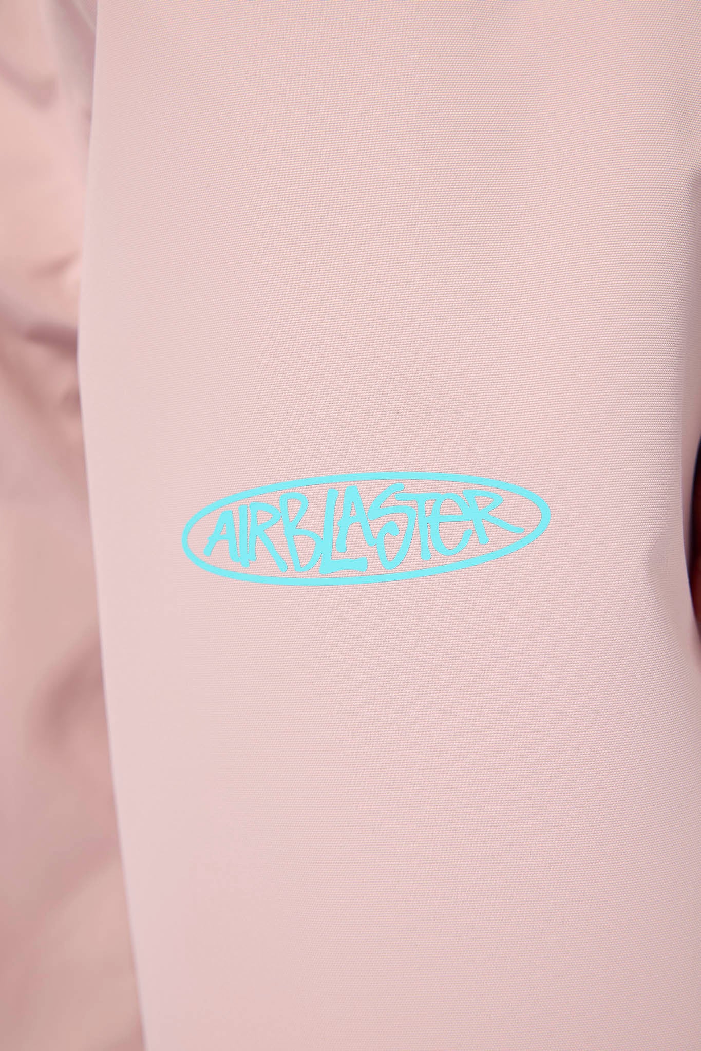 A close-up of a light pink garment featuring a light blue 'AIRBLASTER' logo printed on the chest.