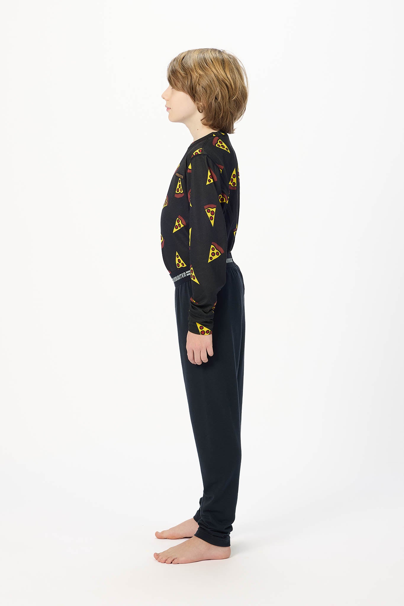 Youth model wearing black base layer bottoms,standing sideways.