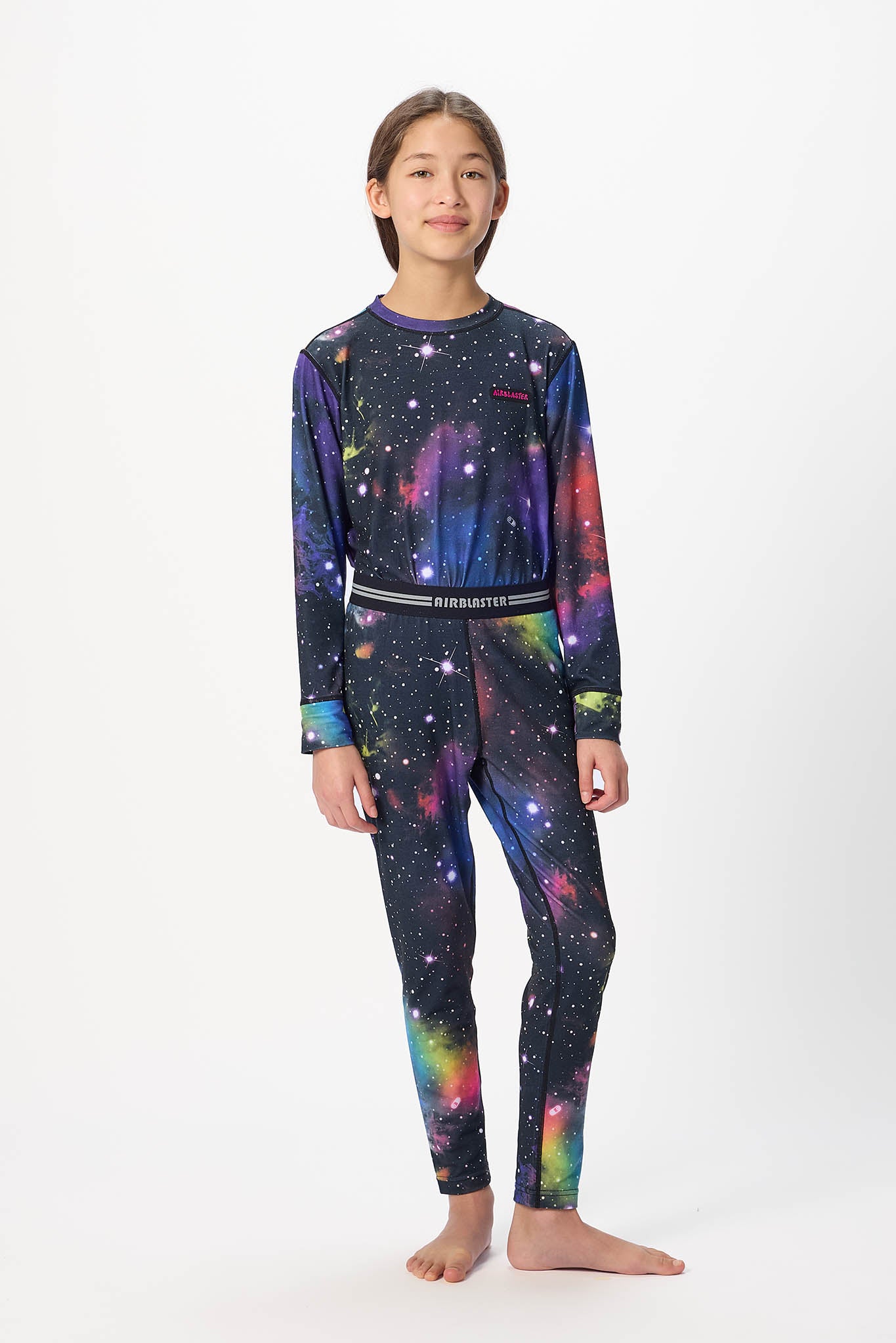 Youth standing center frame, looking away wearing black with far, youth base layer bottoms with white background.  
