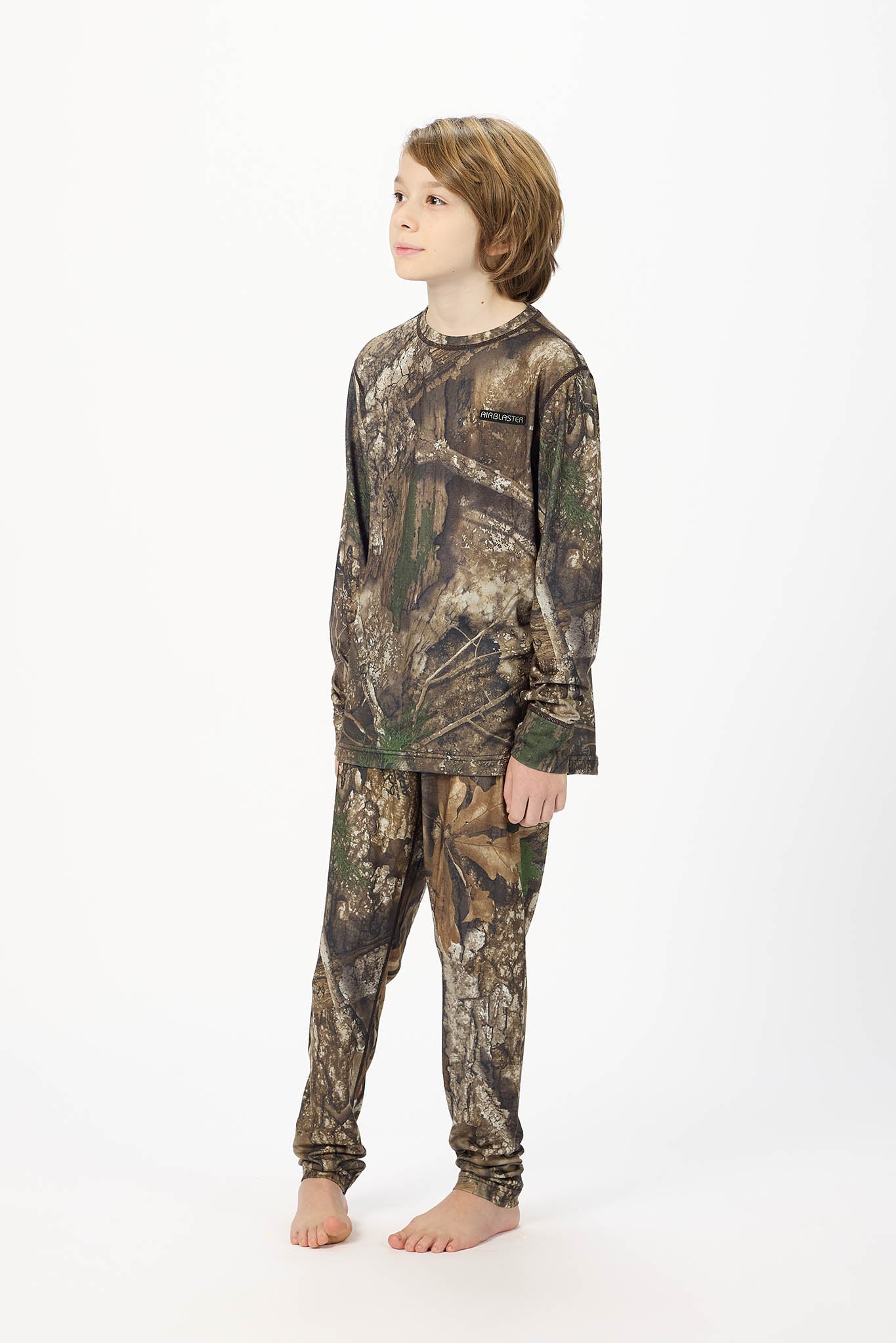 A child model wearing a camouflage long-sleeve shirt and matching pants, standing against a plain white studio background.