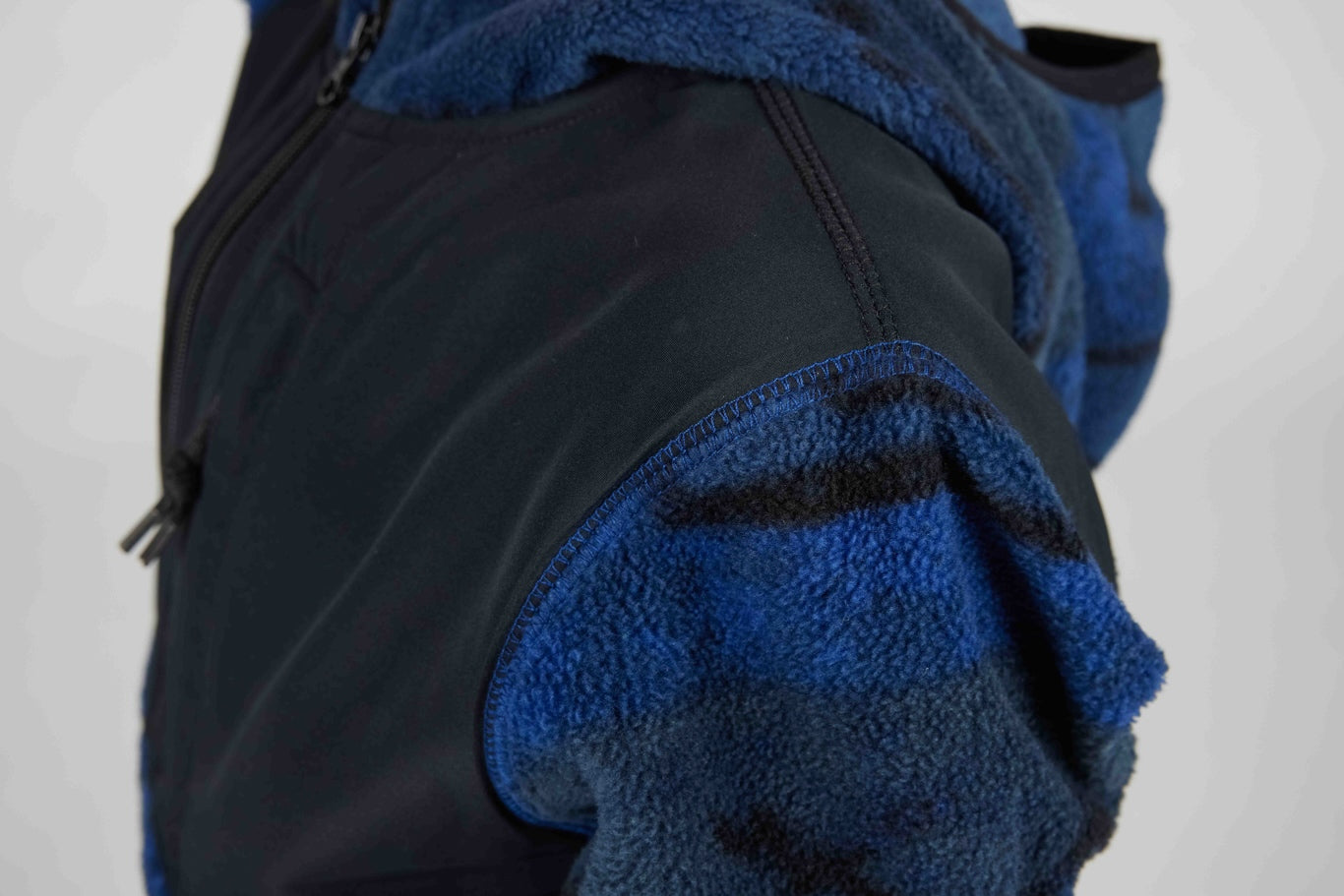 Close-up of a hooded jacket showing a dark navy outer shell and a bright blue fleece-lined hood and shoulder area.