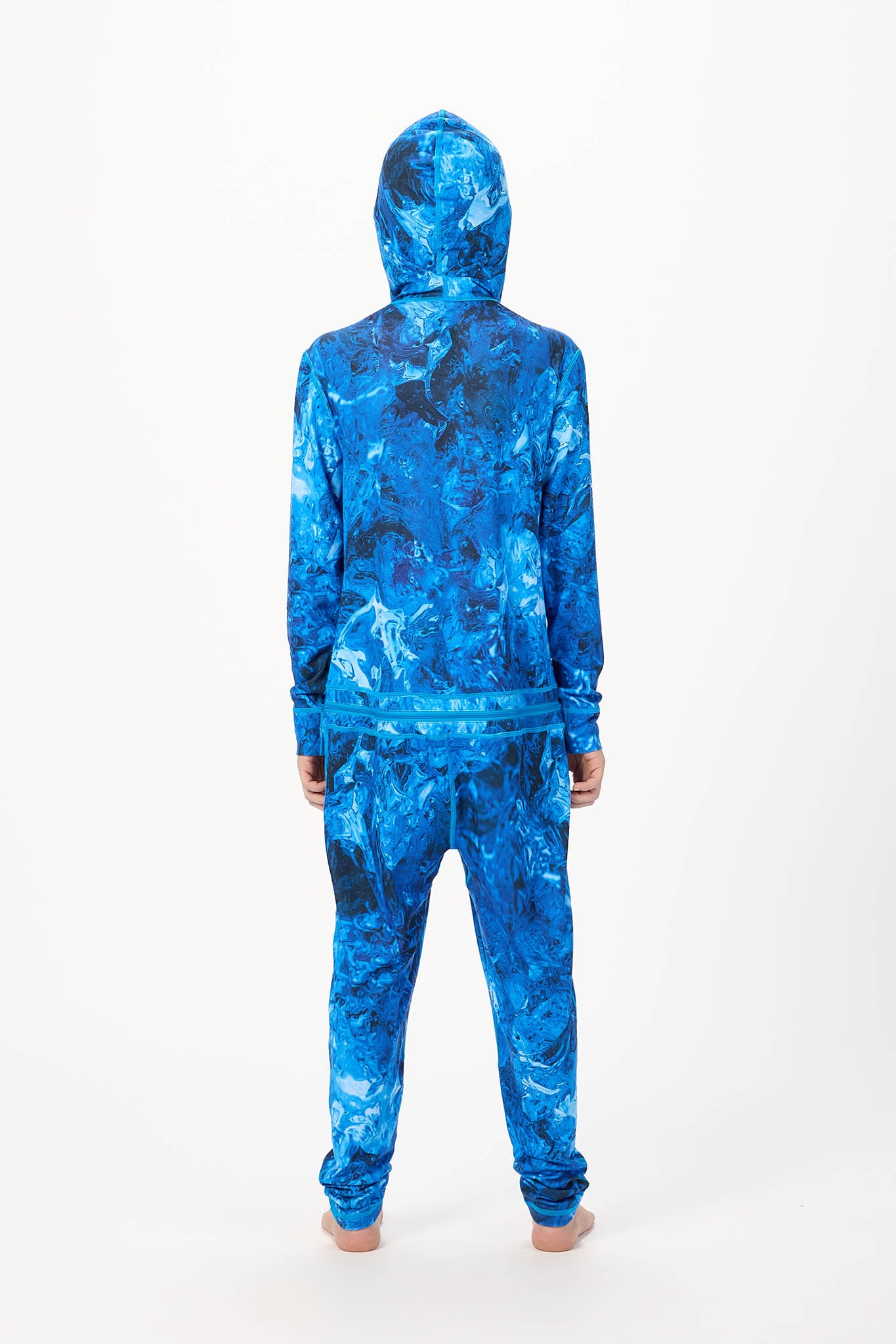 A person viewed from the back wearing a full-body hooded tracksuit with an abstract blue and black marbled pattern, standing against a plain white studio background.