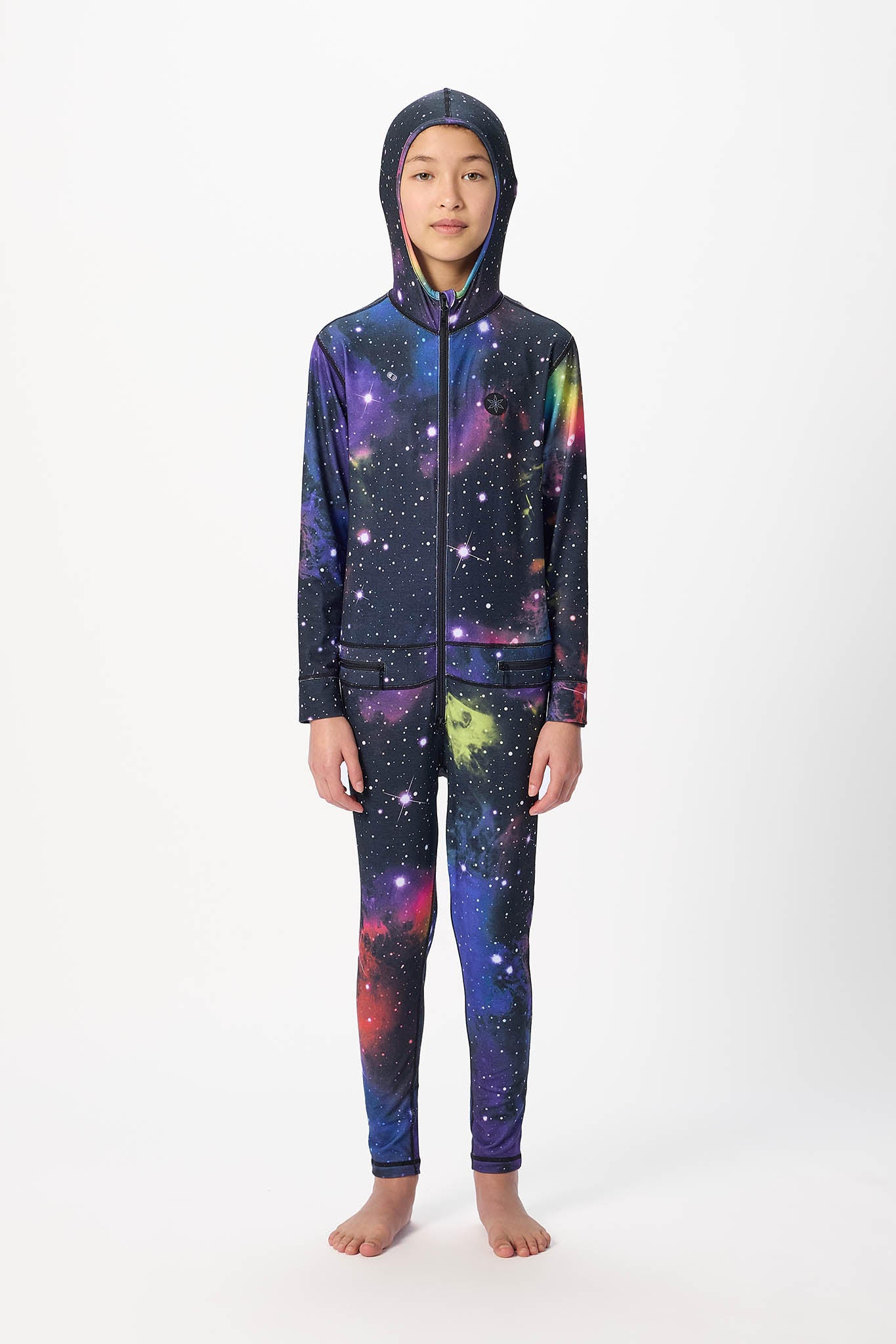 A child model wearing a matching hooded zip-up sweatshirt and leggings set with a vibrant galaxy print, standing against a plain white studio background.