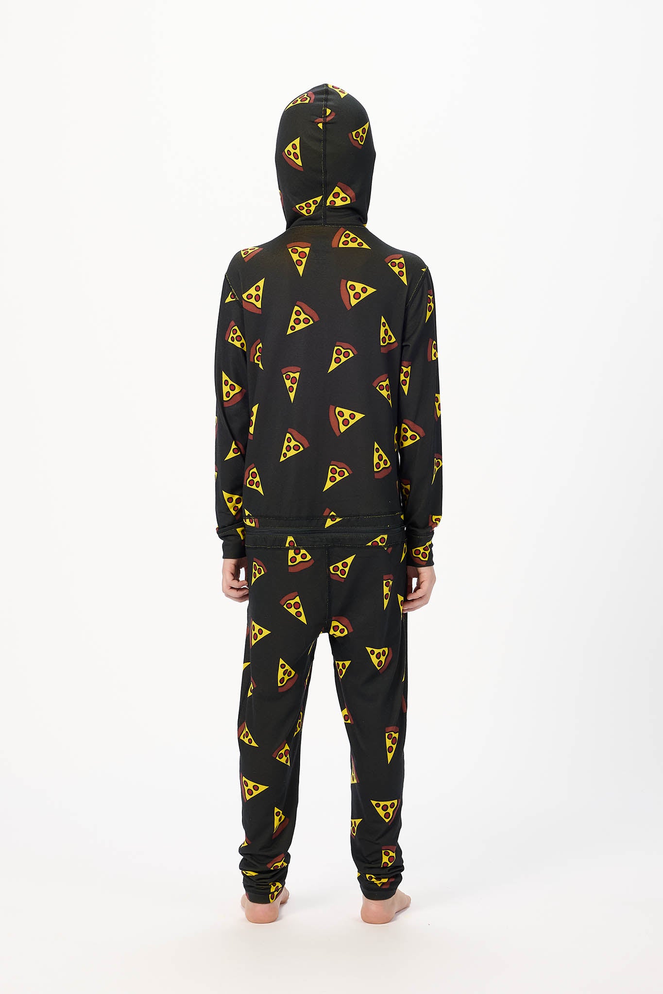A child standing with their back to the camera, wearing a matching black hooded sweatshirt and sweatpants set with a yellow and red pizza slice pattern, on a white studio background.