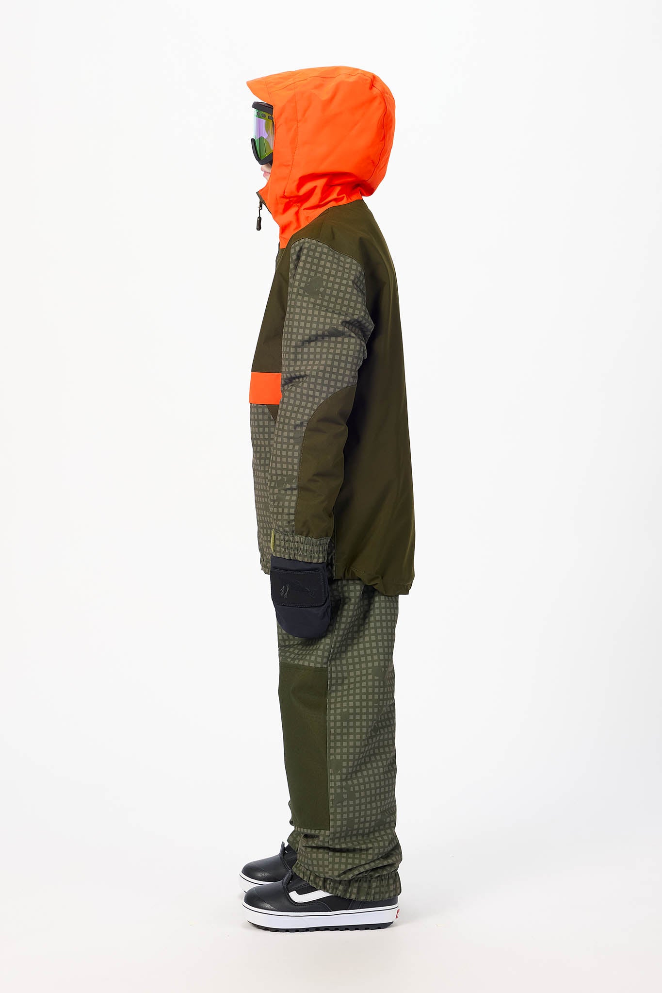 A child model shown in profile wearing a multi-colored outdoor jacket and matching patterned pants, featuring an orange hood, olive green panels, and a small orange chest patch, set against a plain white studio background.