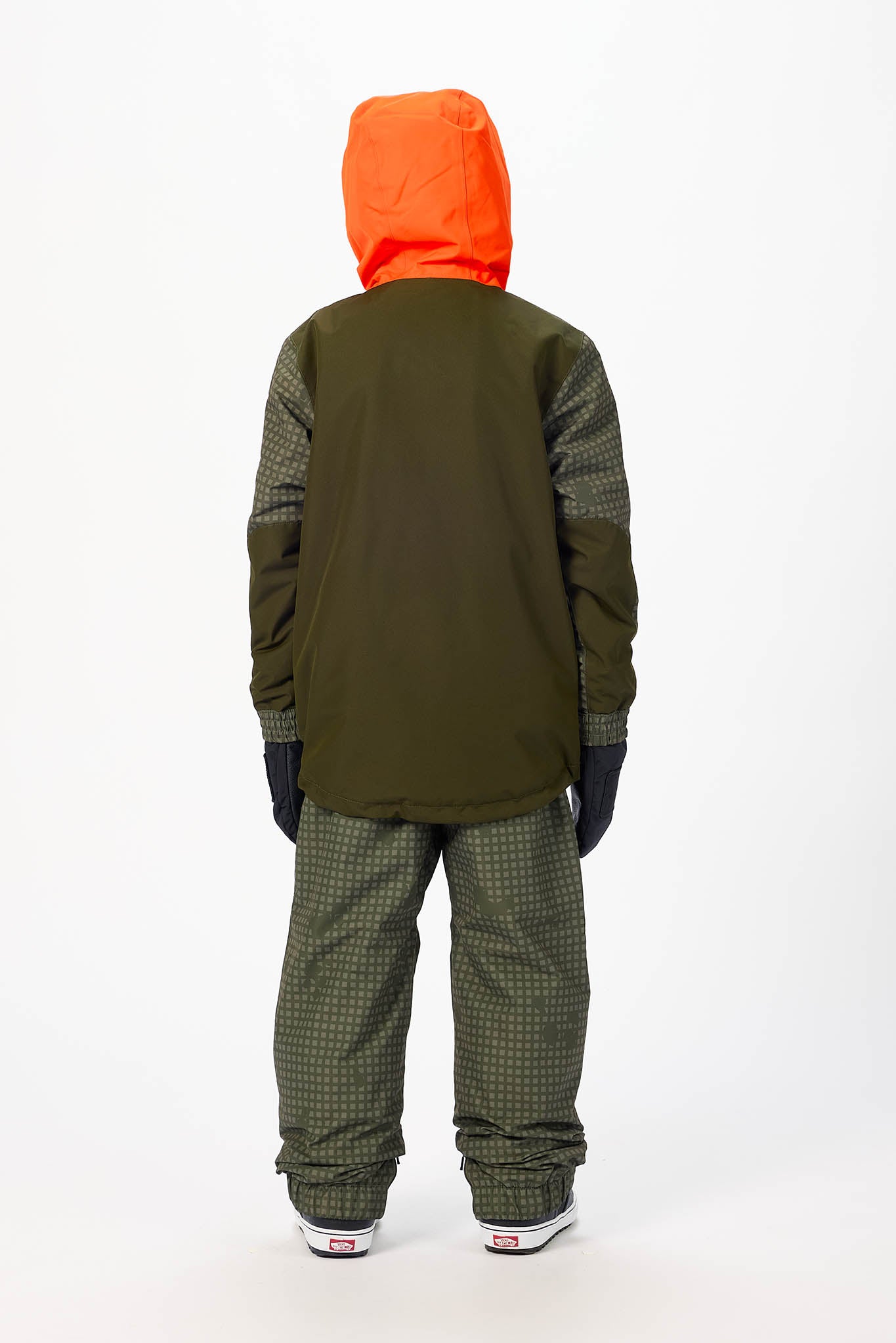 A child viewed from the back wearing a dark olive green jacket with patterned sleeves, a bright orange hood, olive green patterned pants, black gloves, and white sneakers, set against a plain white studio background.